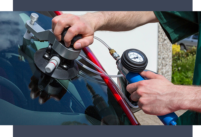 A person is using a gauge to check the windshield of a car.